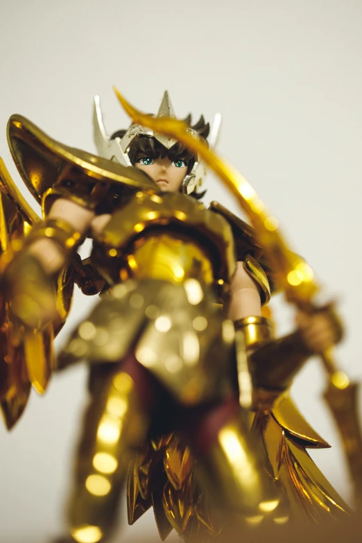 a small action figure with a gold armor holding a golden gun