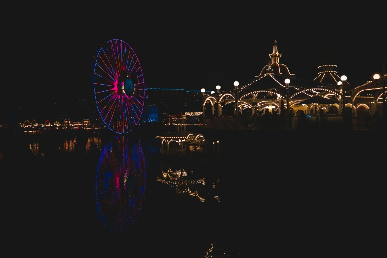 illuminated ferris wheel reflected in water at night