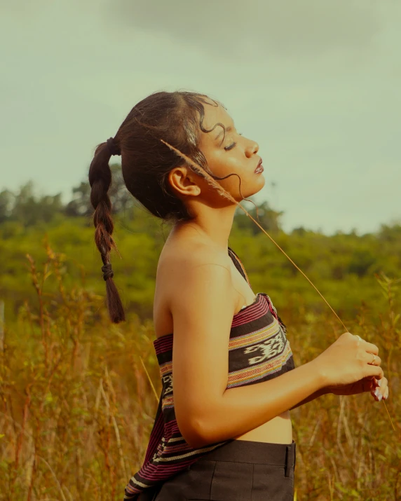 a young woman in a field is wearing a dress and head scarf