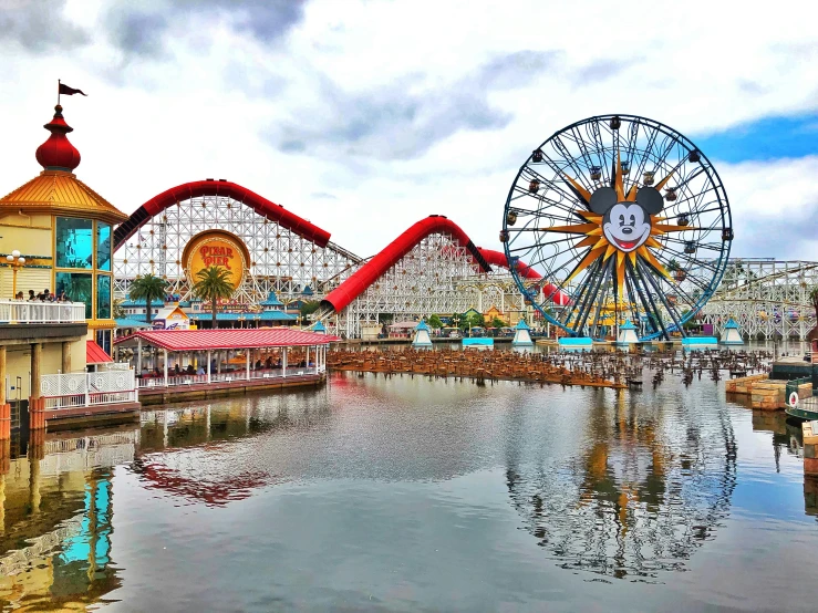 a large ferris wheel next to a small pond with water