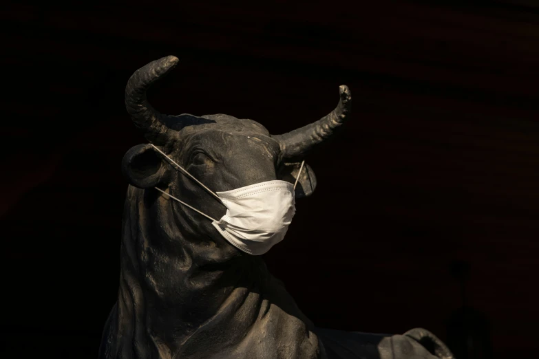an ox statue wearing a surgical mask standing in the dark