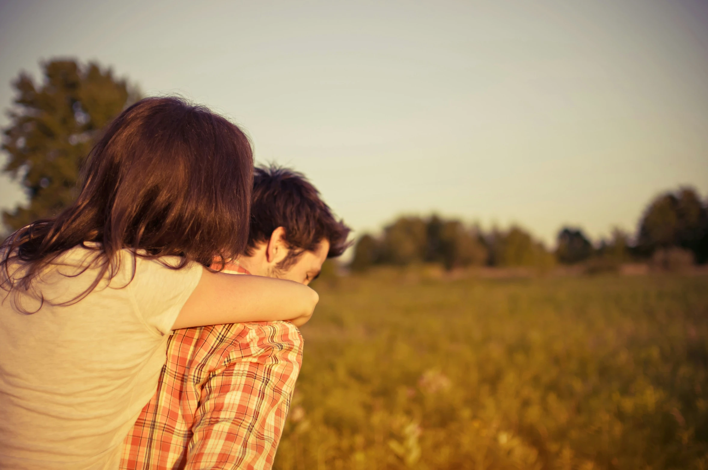 two young people hug in the middle of a large field