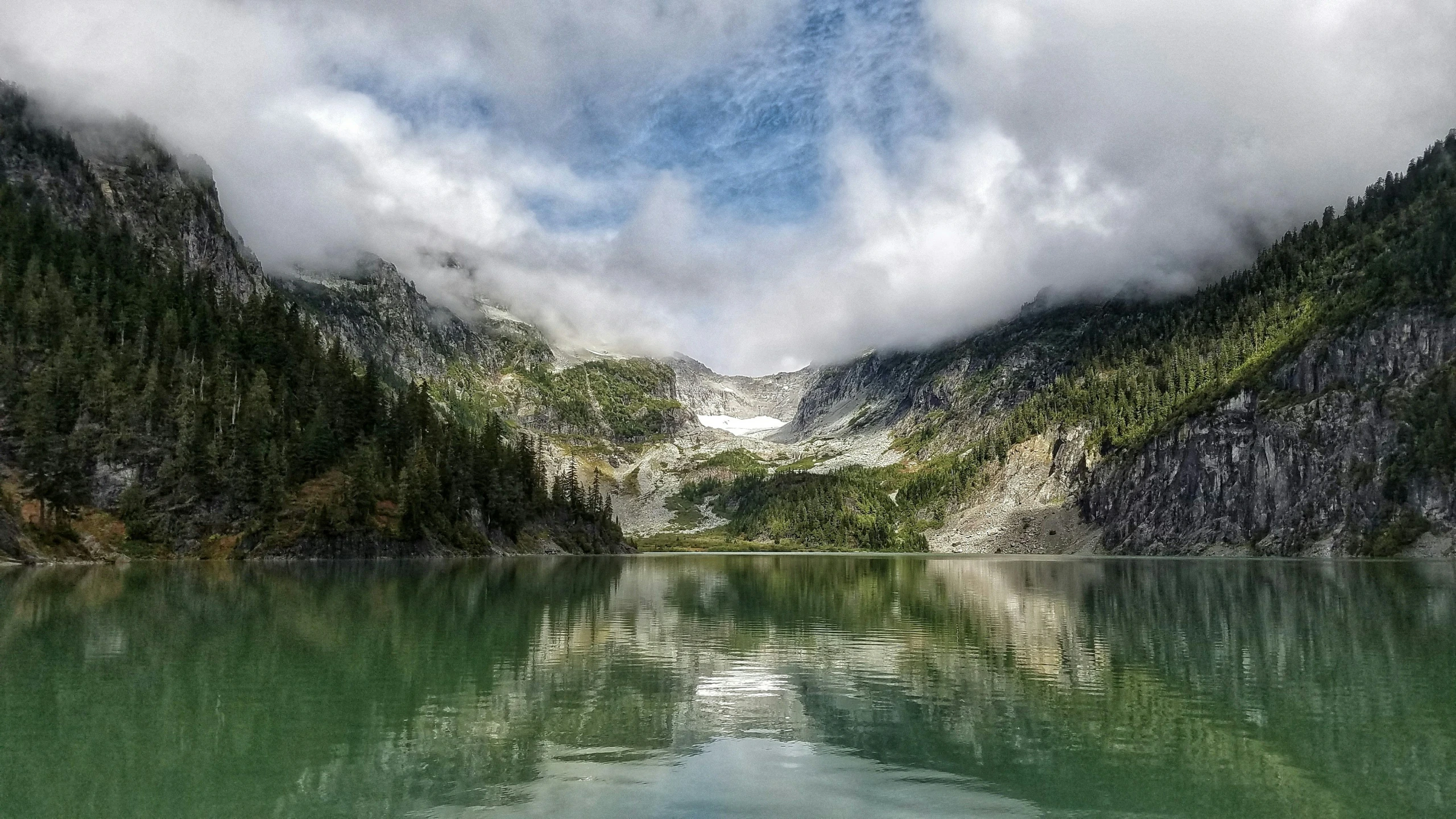 a cloudy mountain lake filled with green water