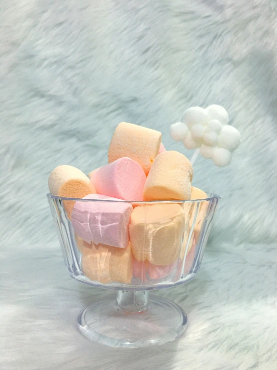 a bunch of marshmallows in a glass bowl on a fur surface