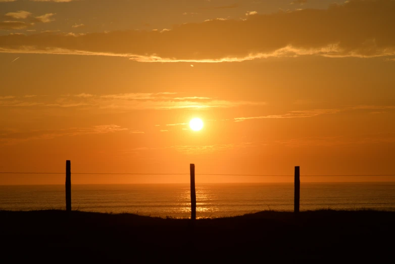 the sun is setting in the distance behind some wires