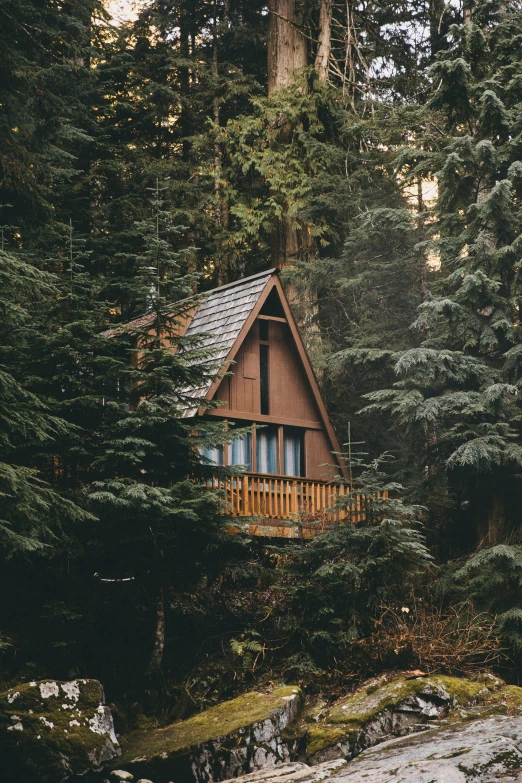 a small wooden house in the woods with a porch
