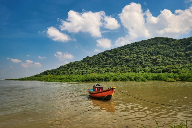 a red boat sitting in the middle of a body of water