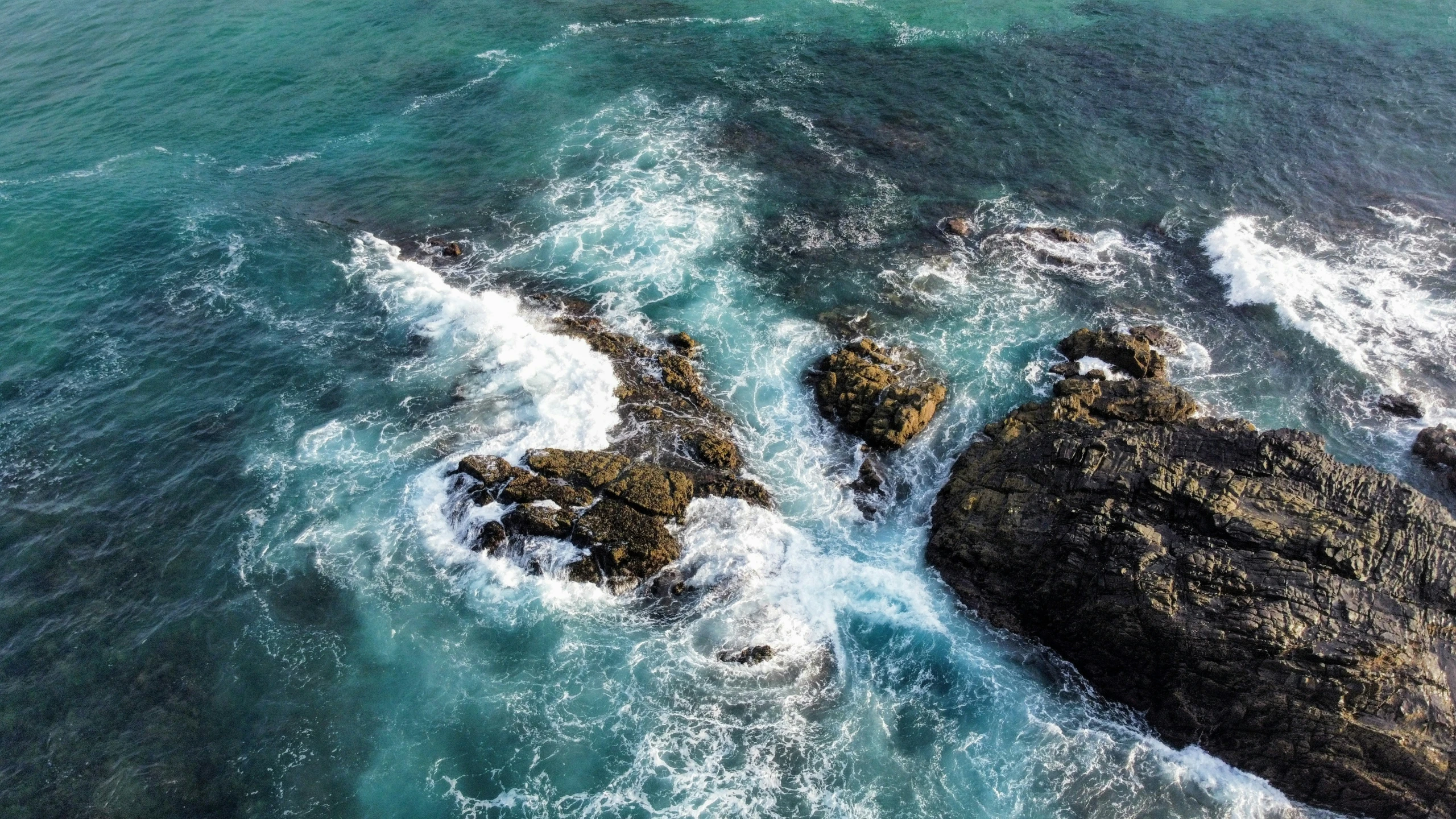 the rocks are near the ocean and have small waves crashing on them