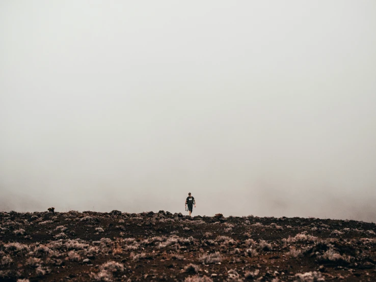 a person stands on the rocky terrain looking at a large object