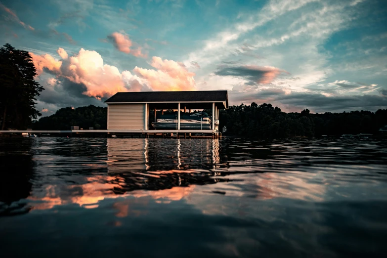 a boathouse sitting on top of the water with a dock under it