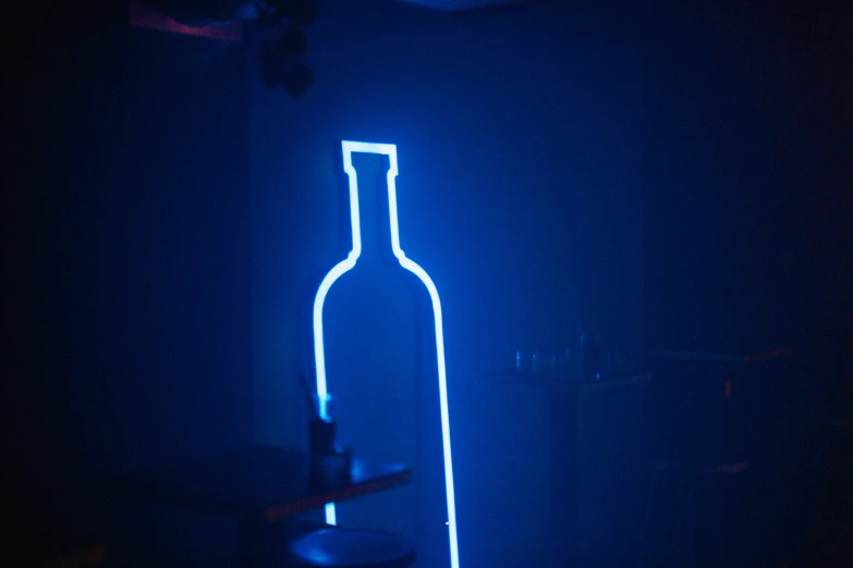 an empty bottle illuminated in the dark of a room