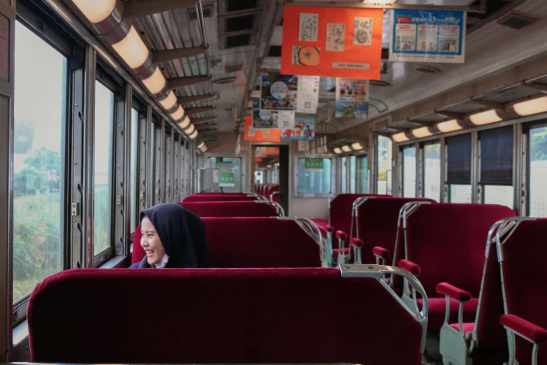 a lady that is sitting on a bus looking at her cellphone