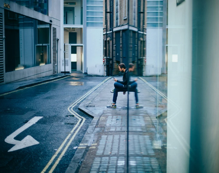 a man sitting on a skateboard is reflected in a mirror