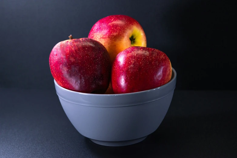 some red apples in a blue bowl on a table