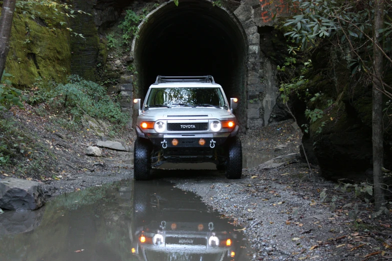 a white truck traveling into a tunnel with its lights on