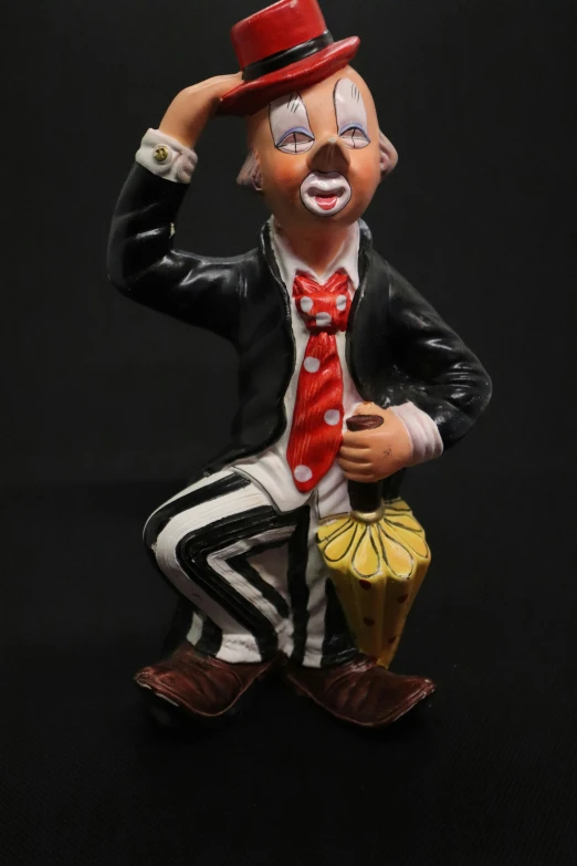 a man in clown mask and suit figurine holding soing in his hand