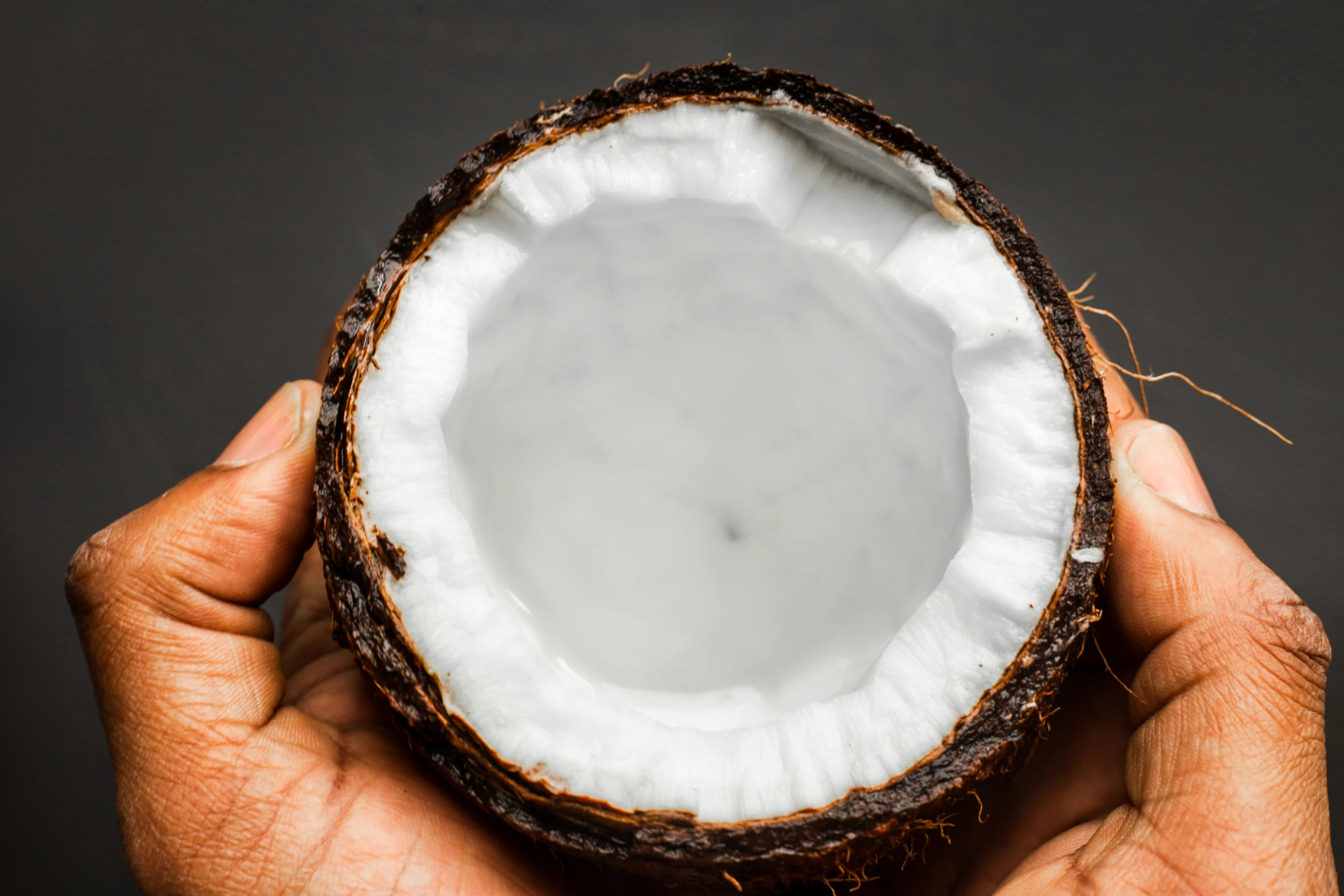 a person holding up a piece of coconut