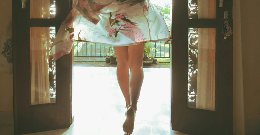 a woman in short white dress walking into a doorway