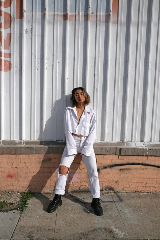 a woman in white standing on a city sidewalk