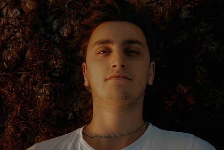 a man laying down in the grass wearing a white shirt