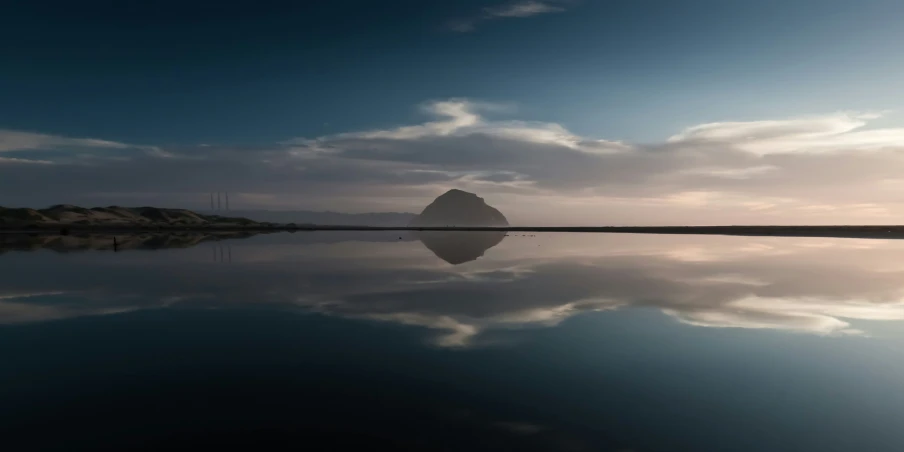 a mountain in the distance is reflected by water