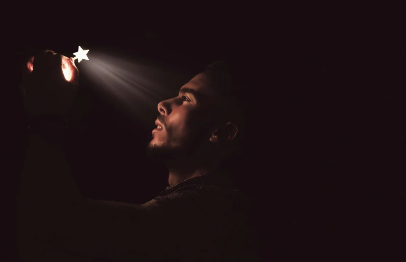 a man looking up at a lighted star in his hand