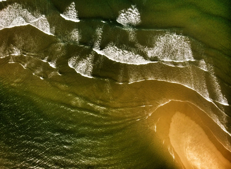 an aerial view of waves crashing into the beach