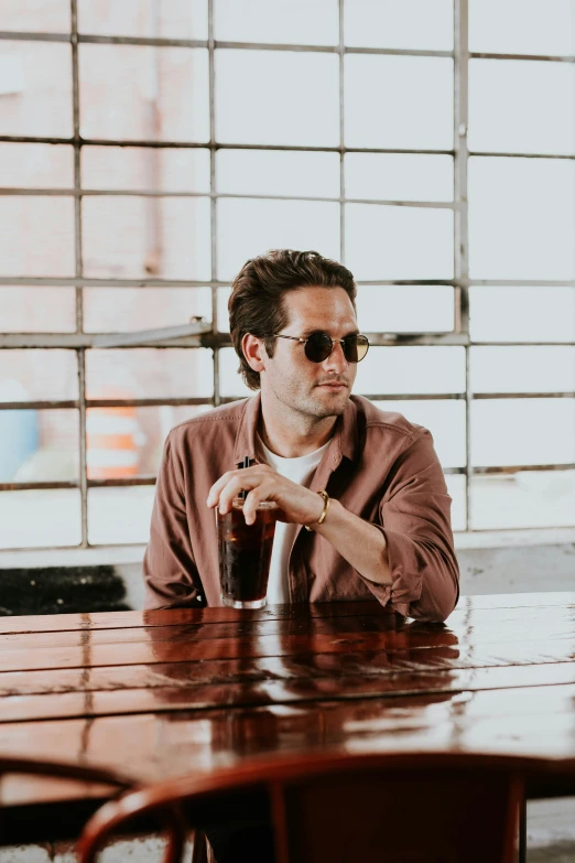 a man sits at a table with a drink in his hand