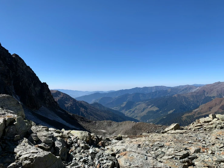 a person standing on a mountain trail looking down at the valley below