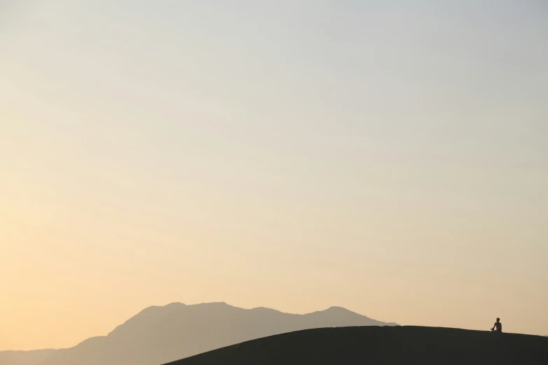 two people walking on top of a grassy hill