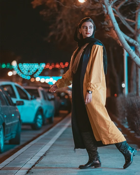 woman walking down the street at night with a long yellow coat on