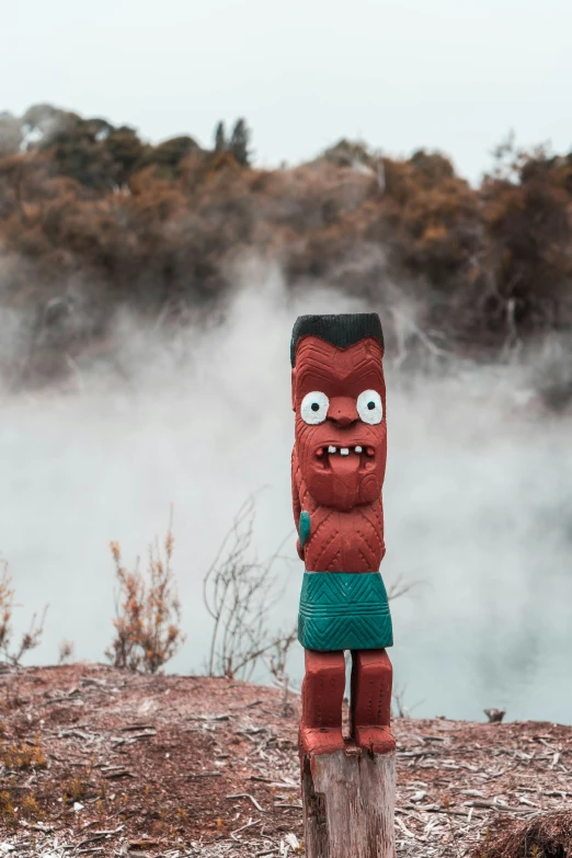 the large wooden statue is painted red with green pants and eyes