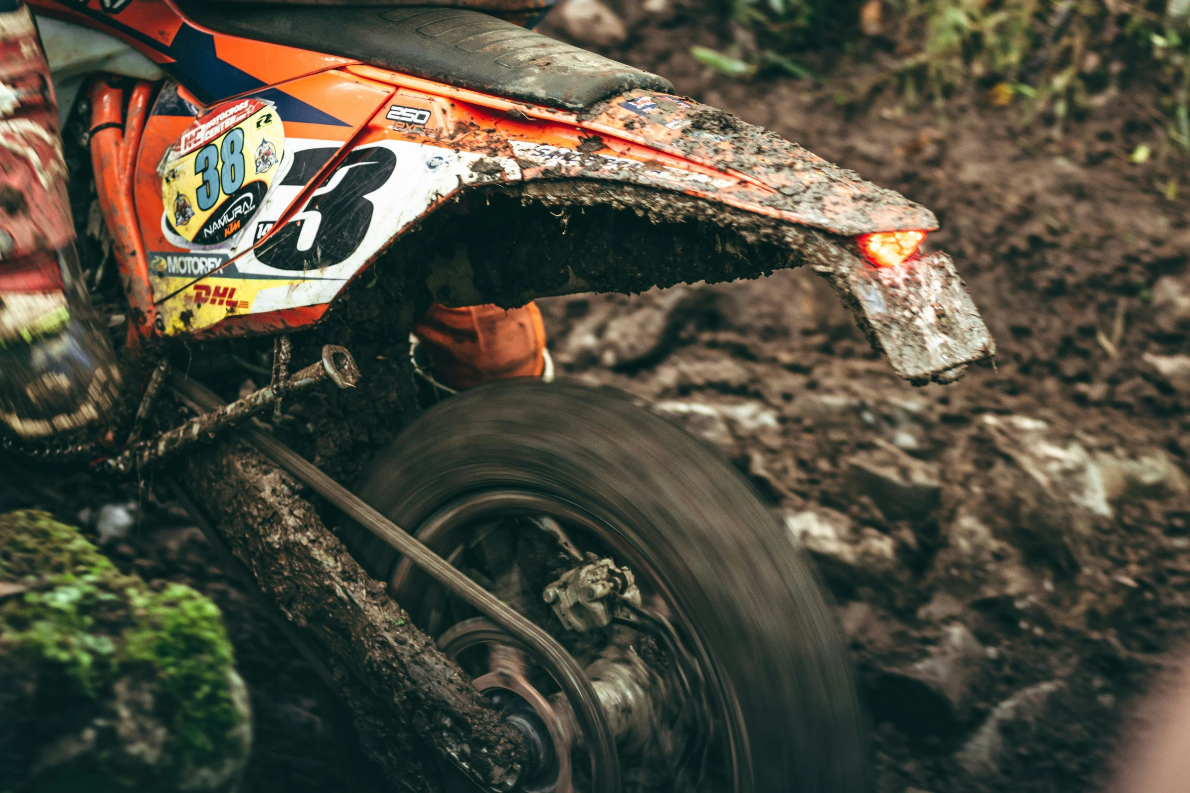 an orange dirt bike riding in the mud