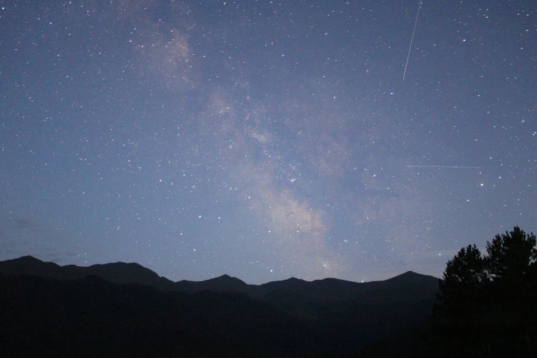 a night sky with stars and mountain range below