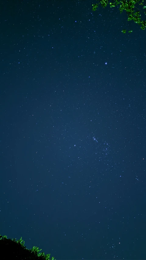 a night sky filled with stars over a hill