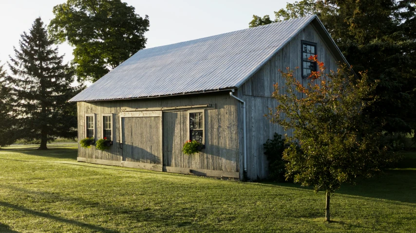 a white barn with windows and doors, sitting in the middle of a grassy field