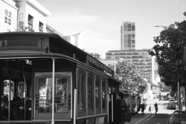 a trolley car traveling down a street past tall buildings