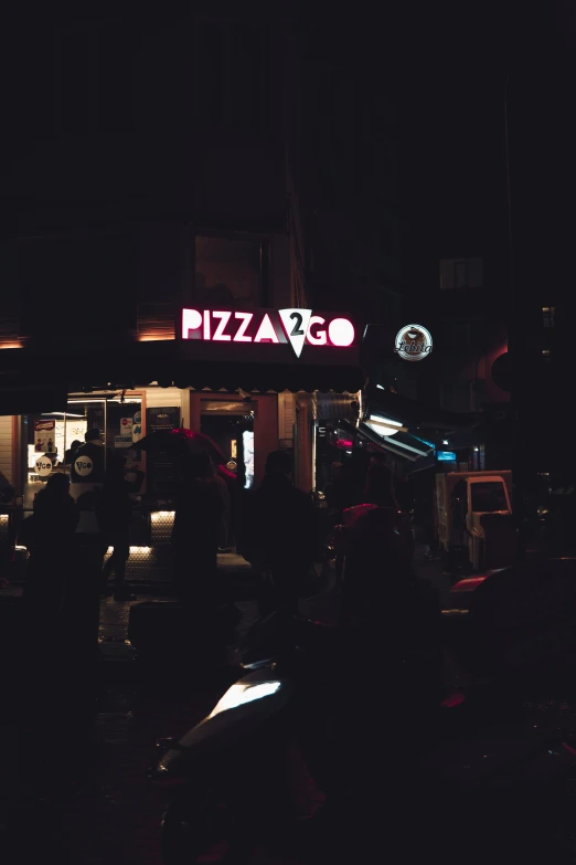 the people in front of a small pizzeria are waiting to eat