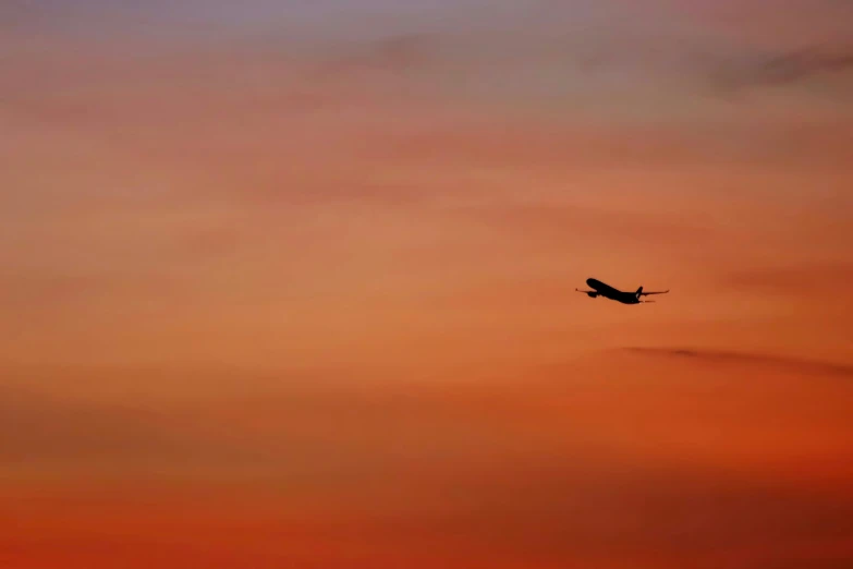 an airplane flying in the sky at sunset