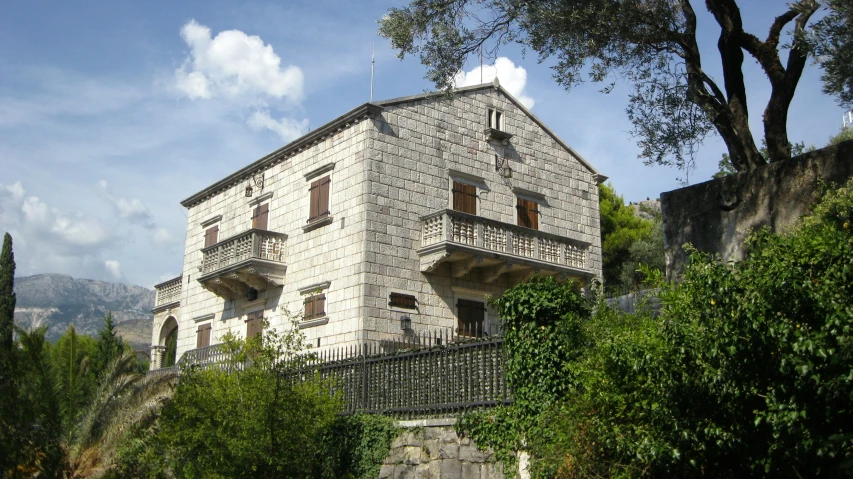 a large house with two levels and tall trees around it