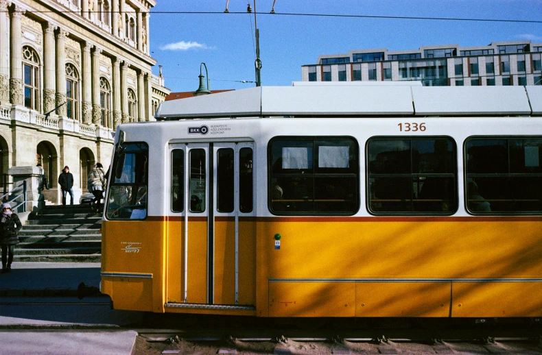 a trolley traveling down a road past a tall building