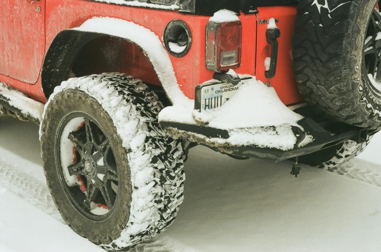 the side view of a red jeep covered in snow