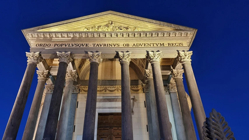 an illuminated building with three columns in front of it