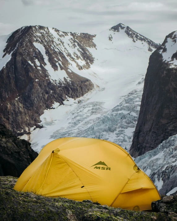 a yellow tent in the mountains near snow