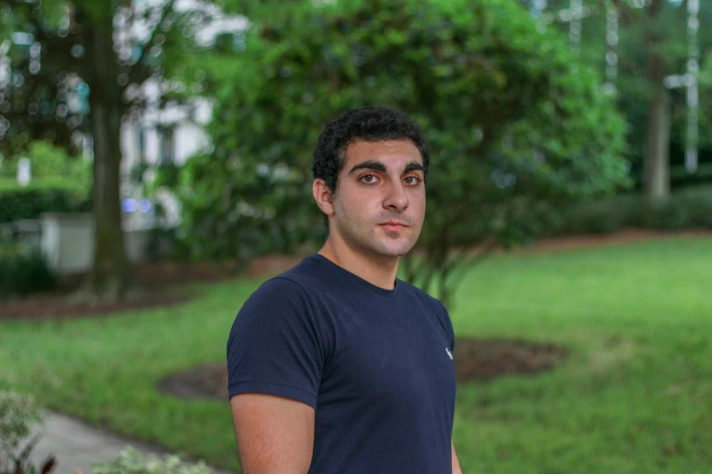 the man stands outside in a park holding his arm around him