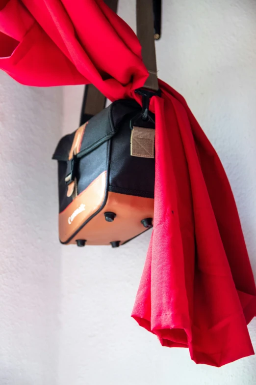 a suitcase and some red cloth are hanging from a hook