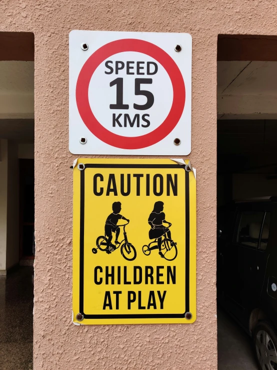 two signs that say caution children at play and speed 15 kms