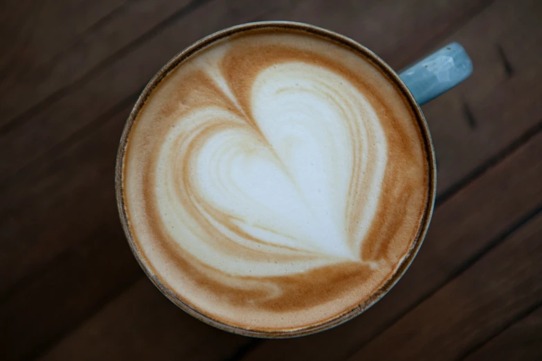 a cup with heart shaped foaming is on a table