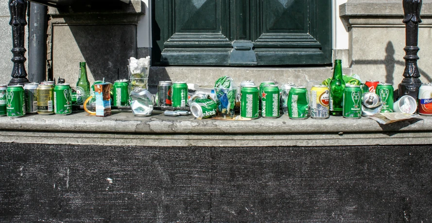 many bottles and cans are stacked on the ground next to a lamp post