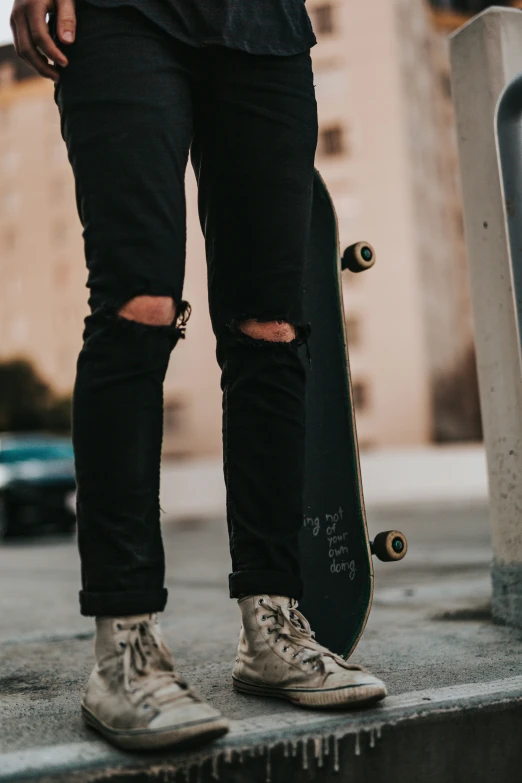 person with grey shoes holding a skateboard on the street